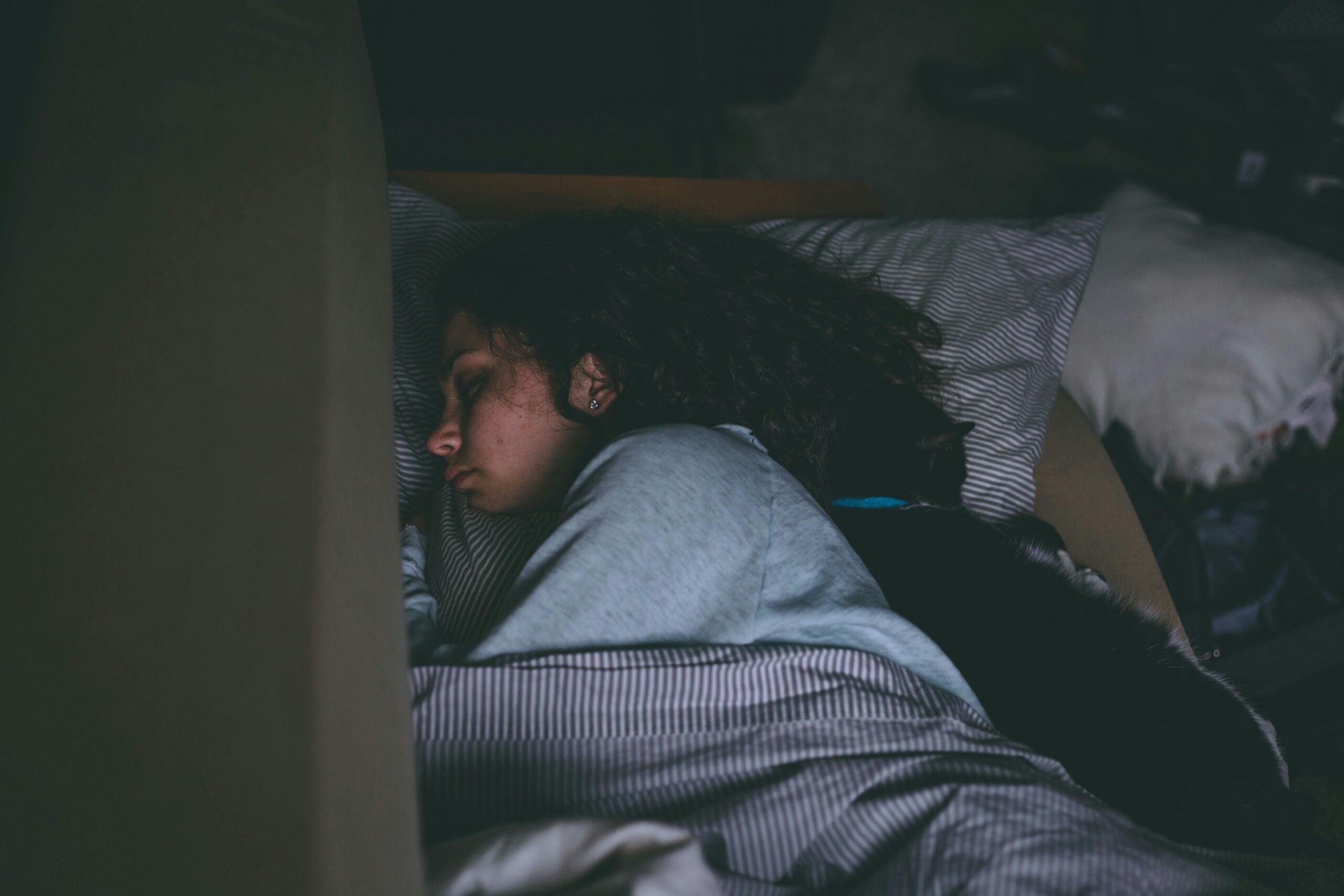 A woman sleeping peacefully with her cat, capturing a serene and cozy nighttime scene.